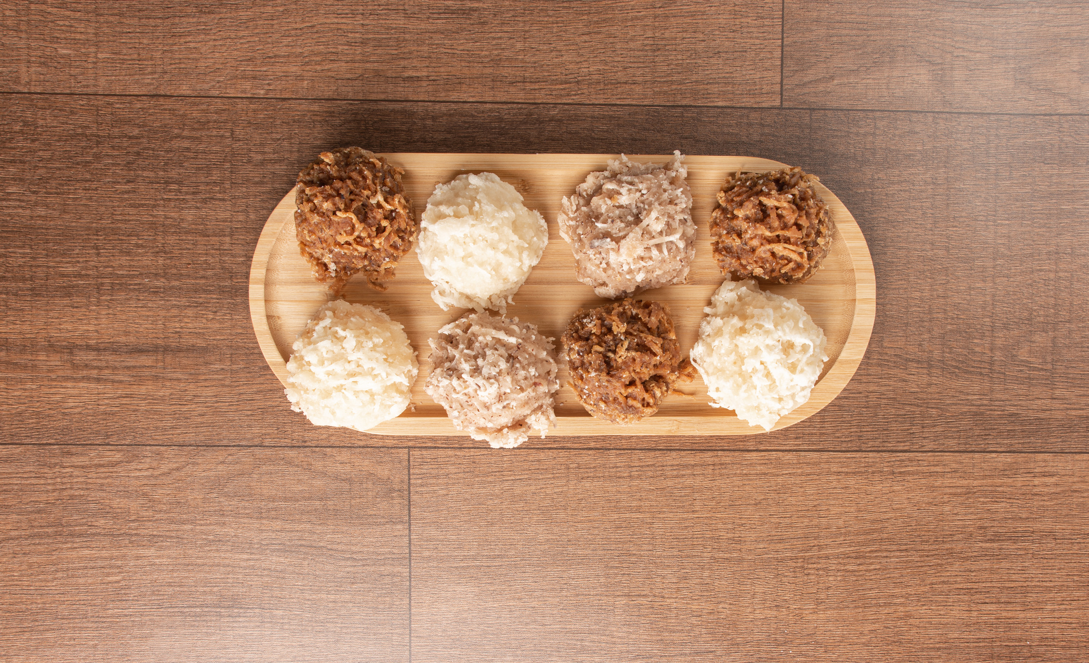Cocada, Coconut candy from Brazil, white and brown cocadas on wooden surface, black background, top view.