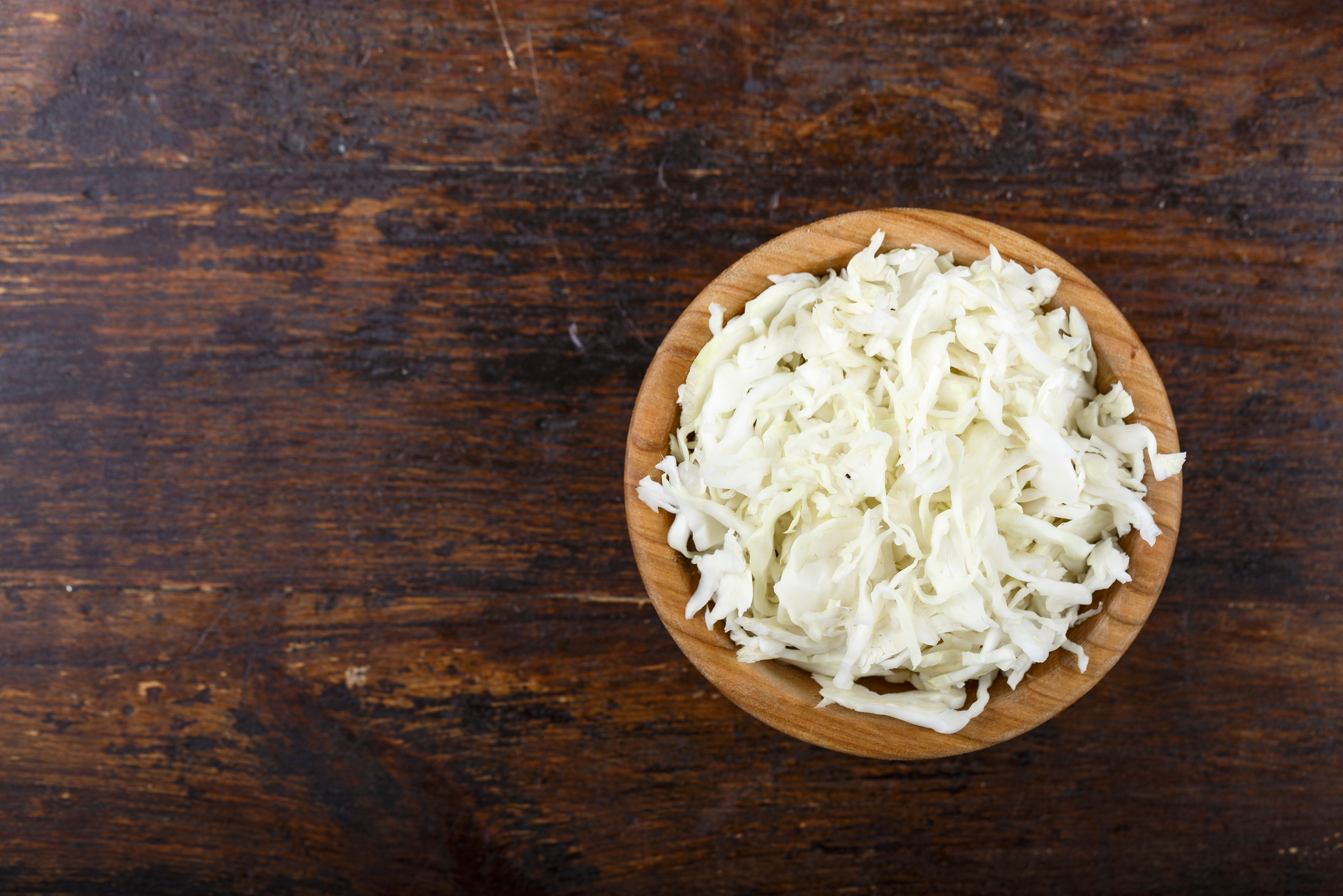 chopped white cabbage in a plate on a wooden background.