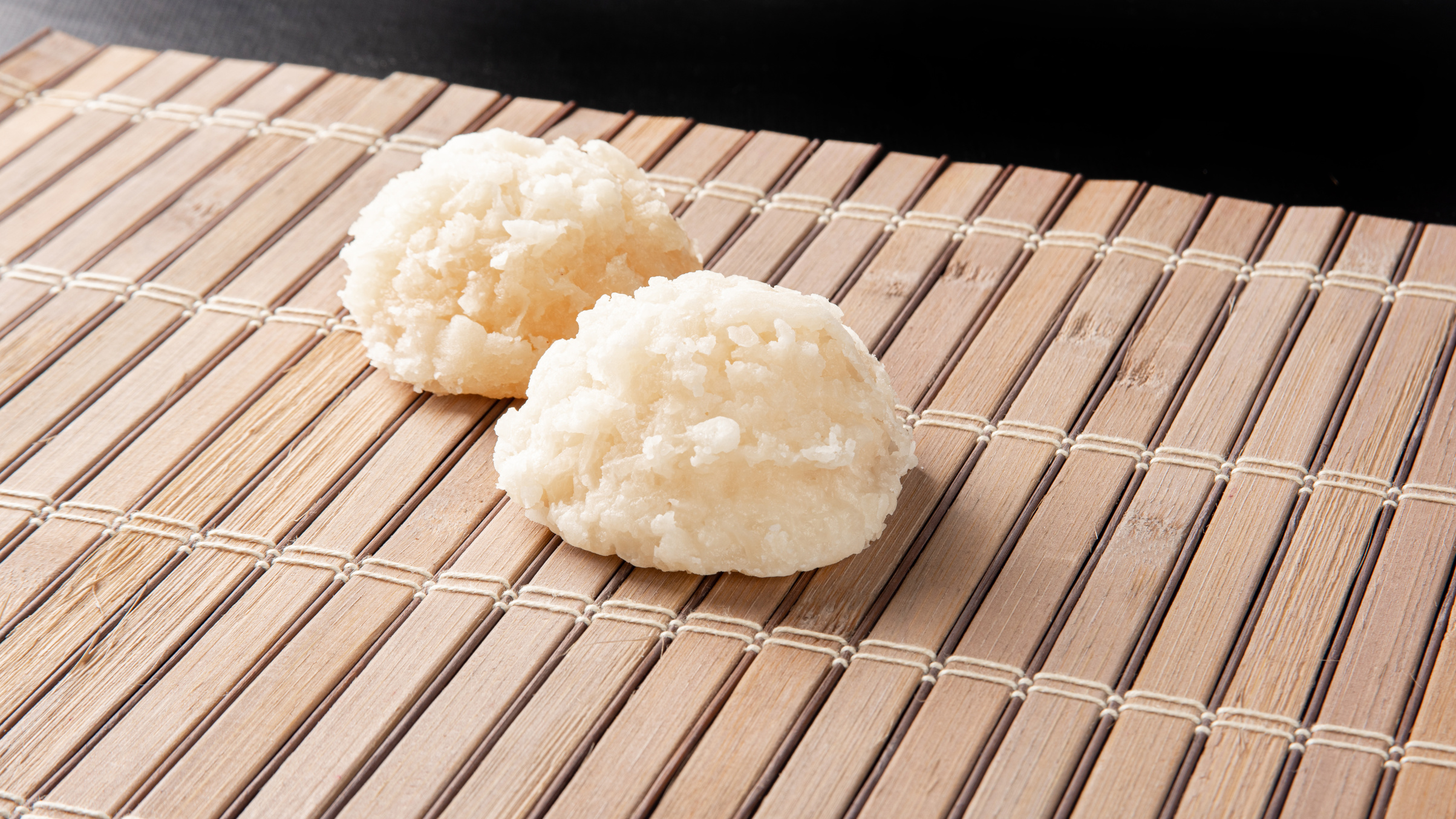 Cocada, Coconut candy from Brazil, white cocadas on wooden mat, black background, selective focus.